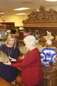 Donna Gantenbein (right) shows a rare art glass vase to a customer at Salado Creek Antiques.
